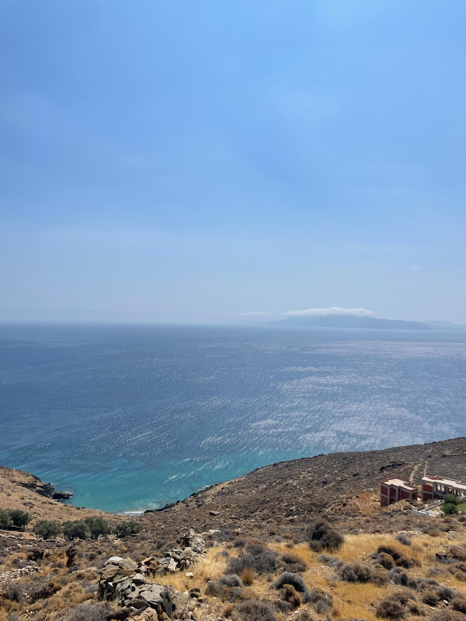 "A breathtaking view of the endless Aegean Sea from Tinos Island, Greece. The deep blue water and clear sky stretch to the horizon, creating a serene and unspoiled landscape."